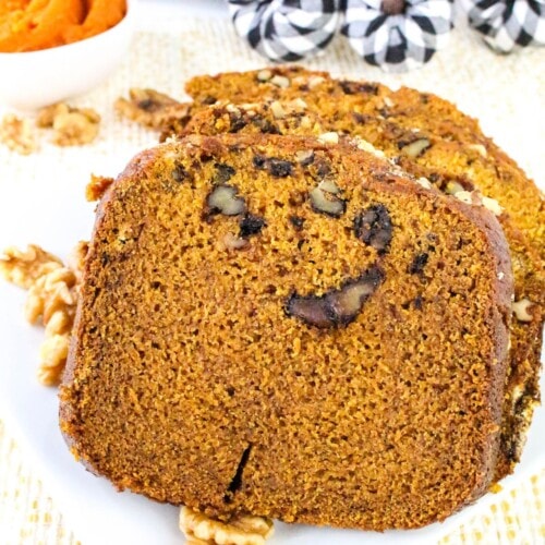 Slices of homemade bread machine pumpkin bread are laying on a white plate.