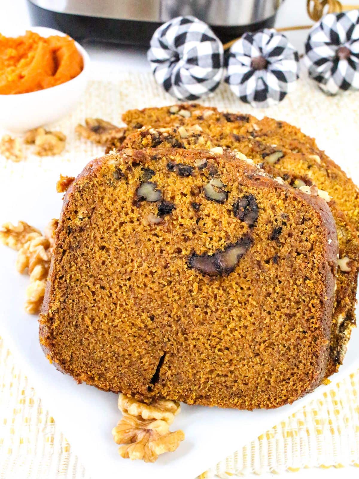 Slices of homemade bread machine pumpkin bread are laying on a white plate.