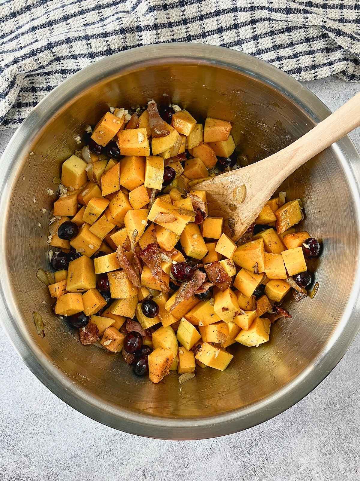 Cubed butternut squash tossed with bacon, cranberries, and seasoning.
