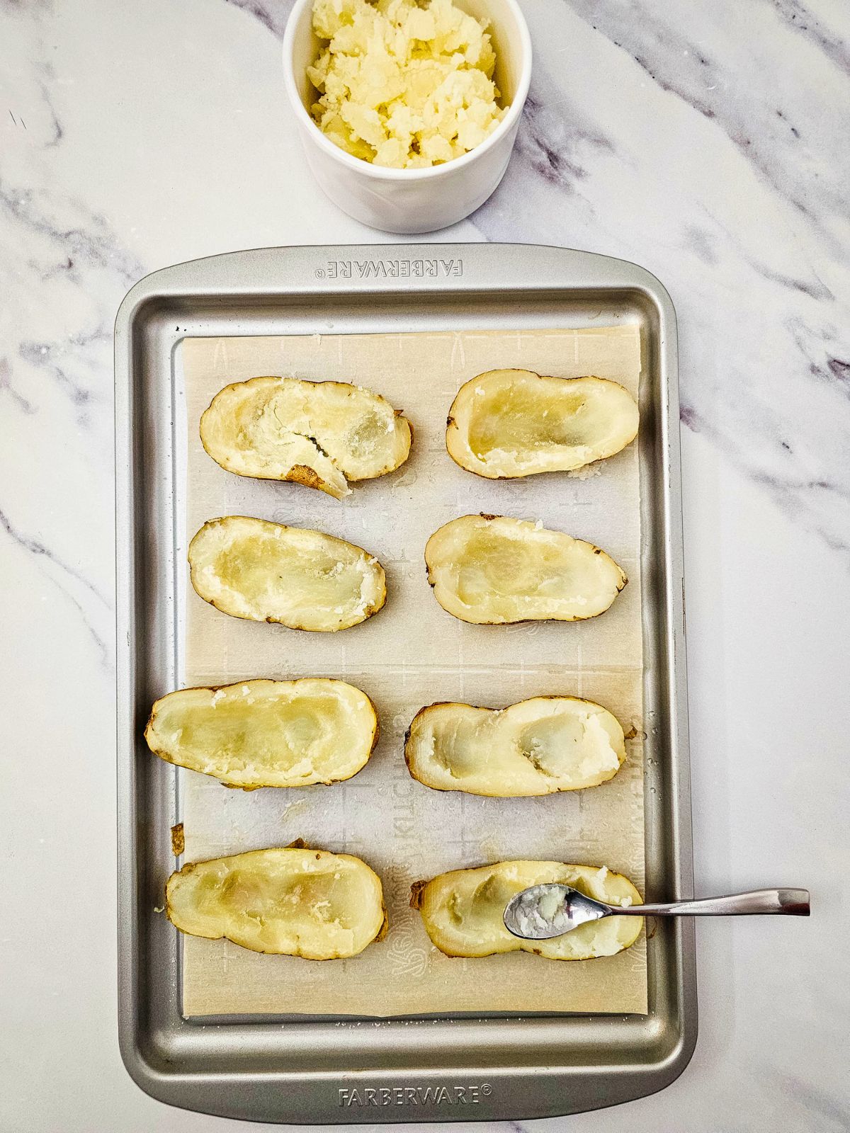 The centers of the baked potatoes have been scooped out with a spoon.