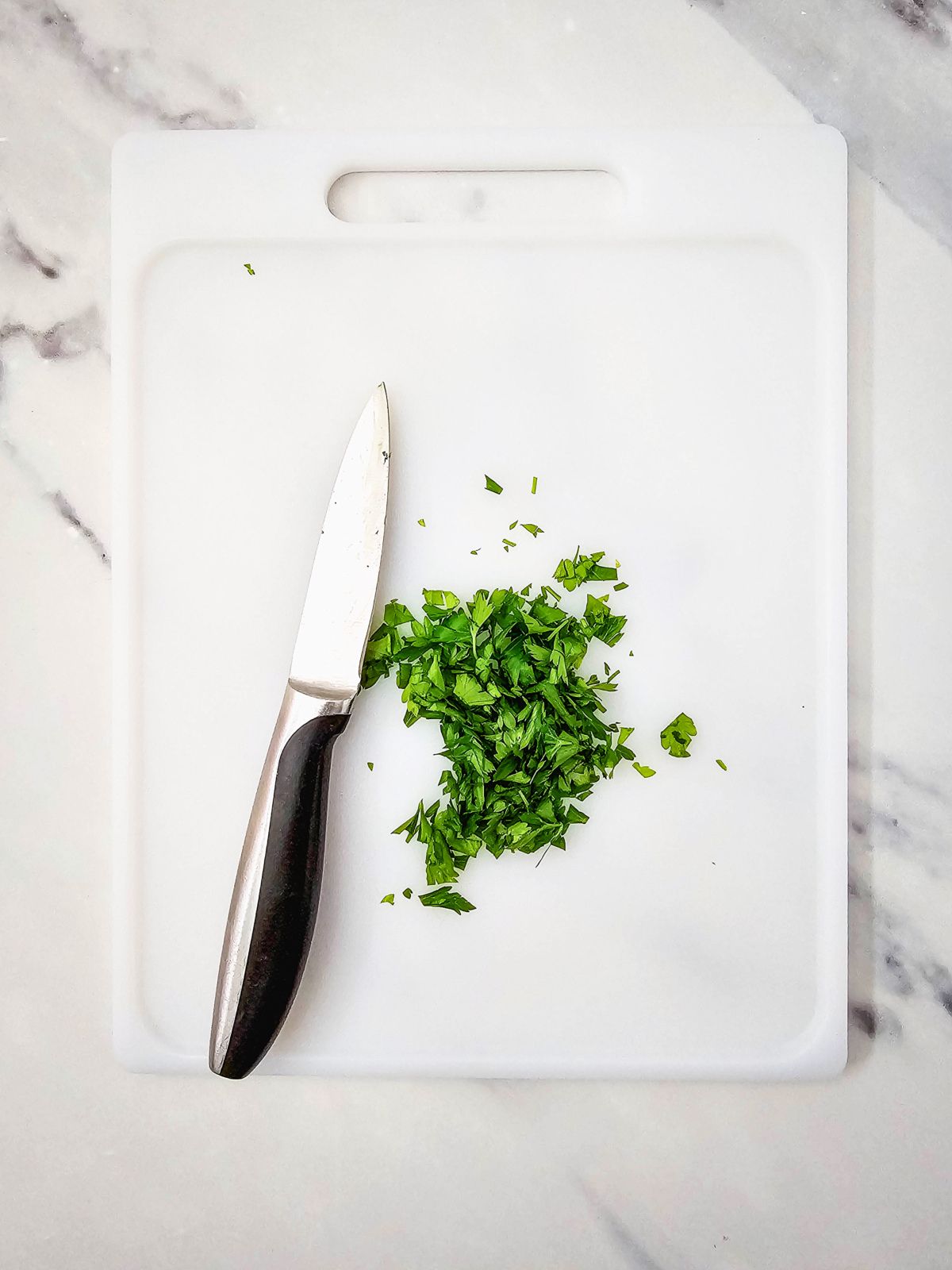 Fresh chopped parsley on a cutting board.