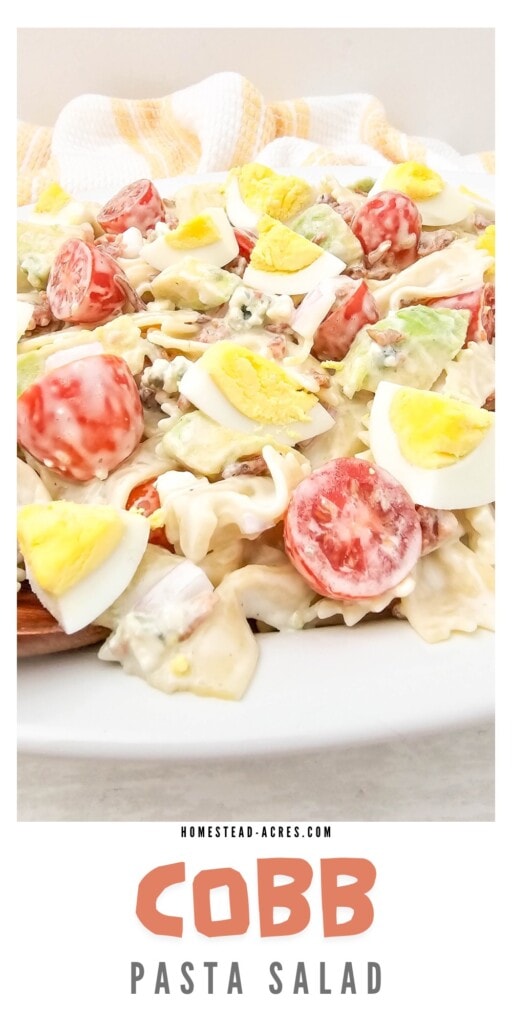 Pasta cob salad with tomatoes and eggs on a platter. The text overlay says Cobb Pasta Salad.