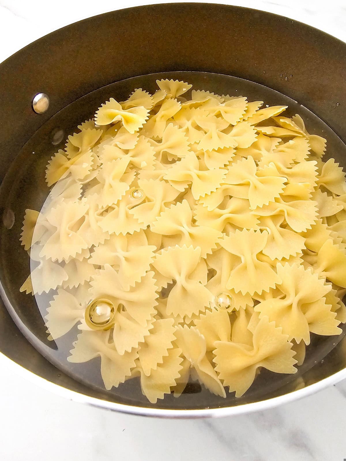 Bowtie pasta is cooking in a large pot.