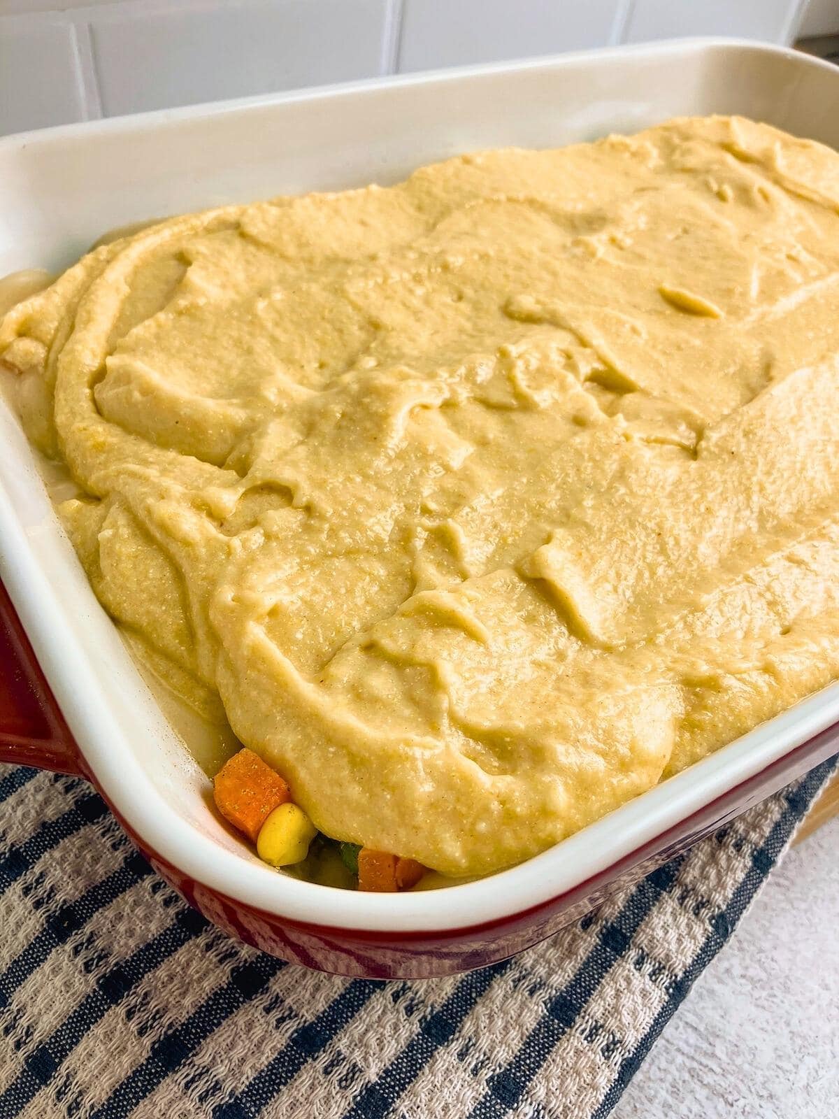 Cornbread batter is poured over the top of the meat and vegetable mixture.