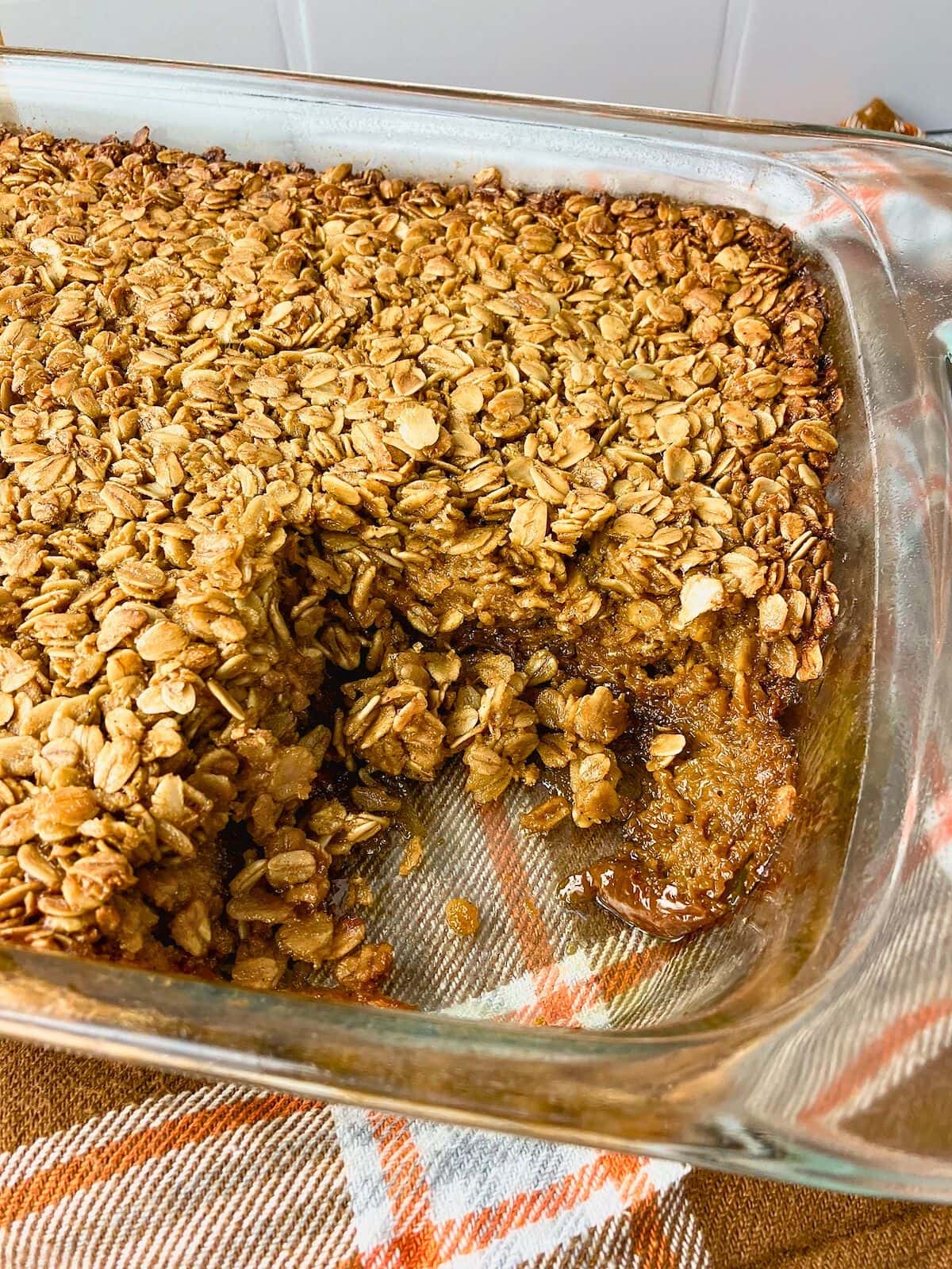 A baking dish of gingerbread baked oatmeal with a slice removed.
