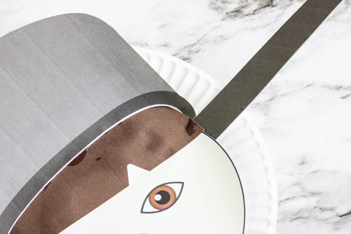 The hat and face have been glued onto the paper plate.