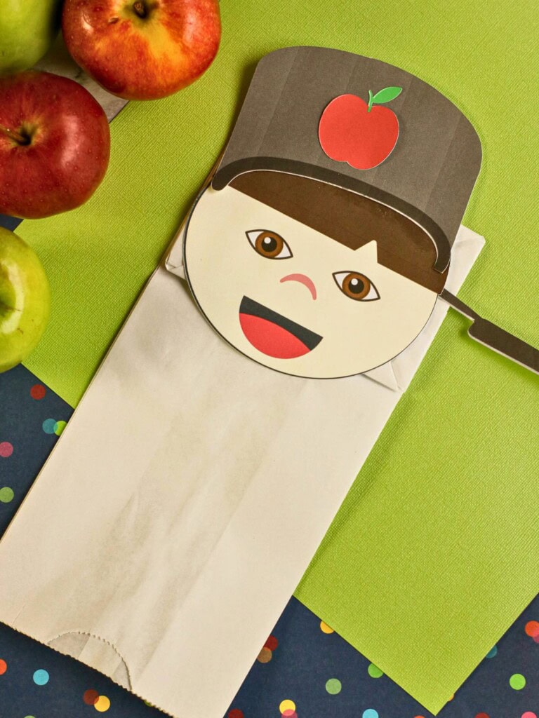 Johnny Appleseed paper bag puppet craft laying on top of a green and patterned paper background.
