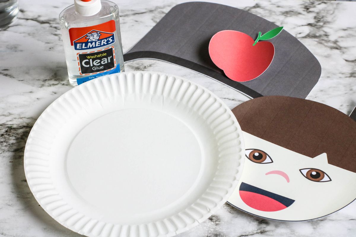Paper plate craft with all the parts of John Appleseed cut apart.