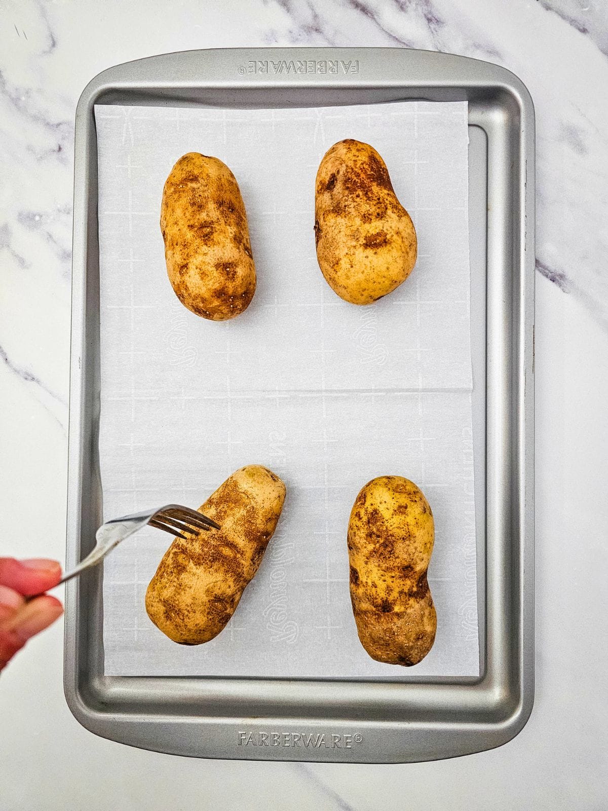 Pricking holes into potatoes with a fork.