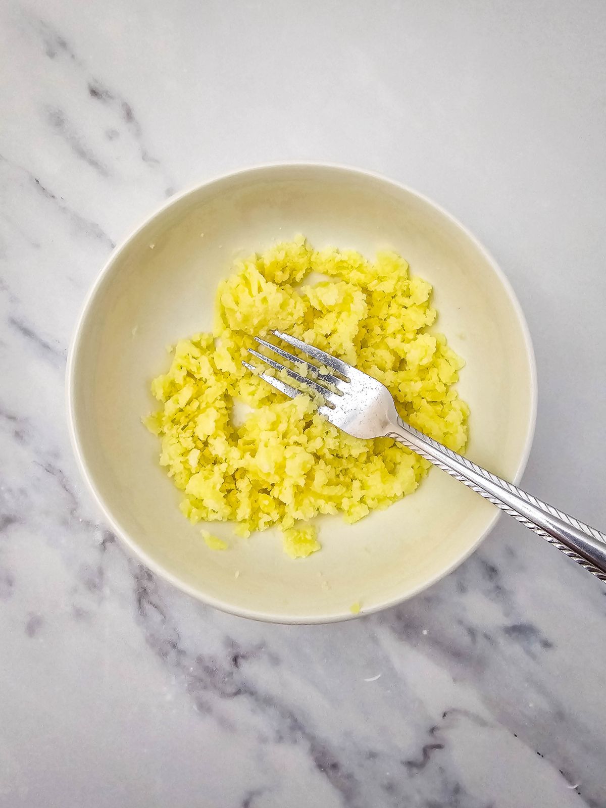 Mashing the potatoes in a bowl with a fork.