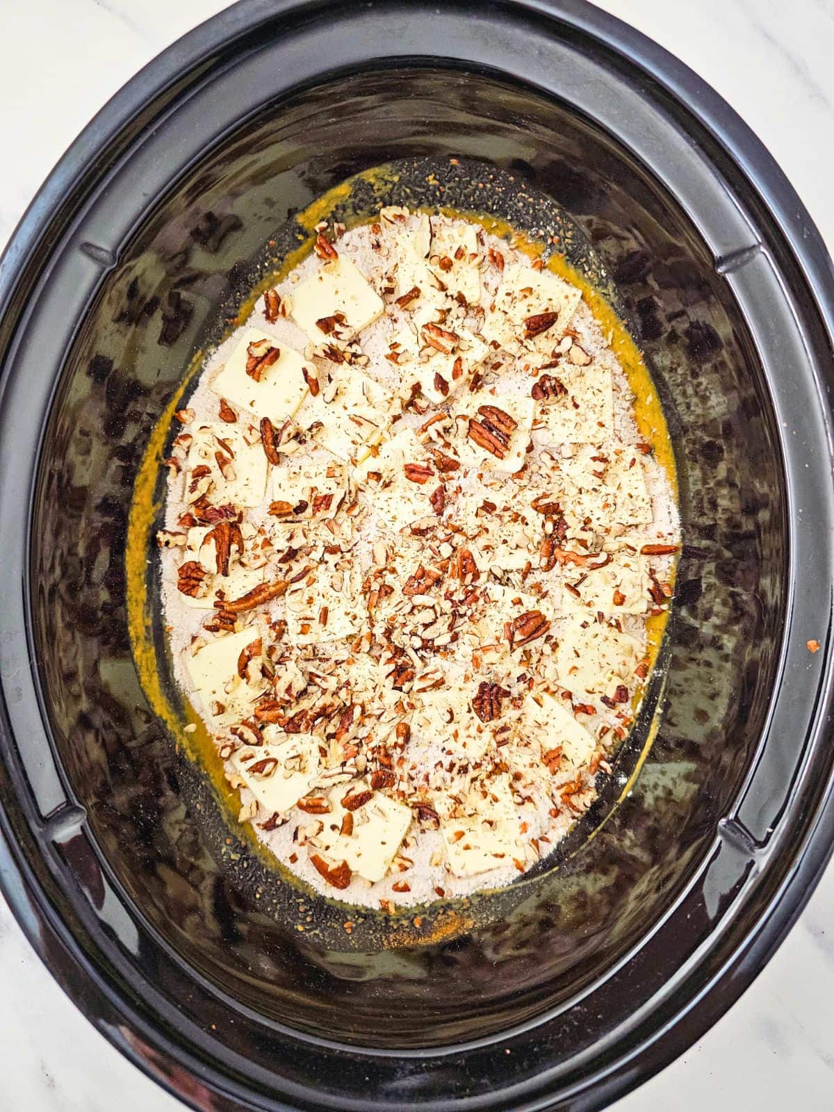 Pecan pieces sprinkled over the top of the cake batter.