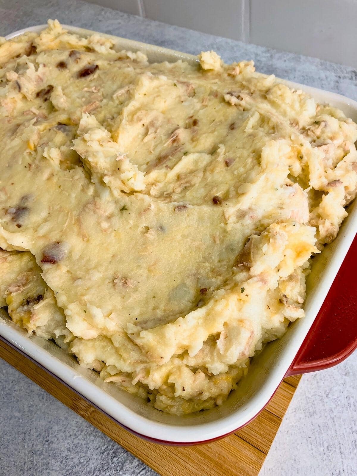 Mashed potatoes are spread into a casserole dish.