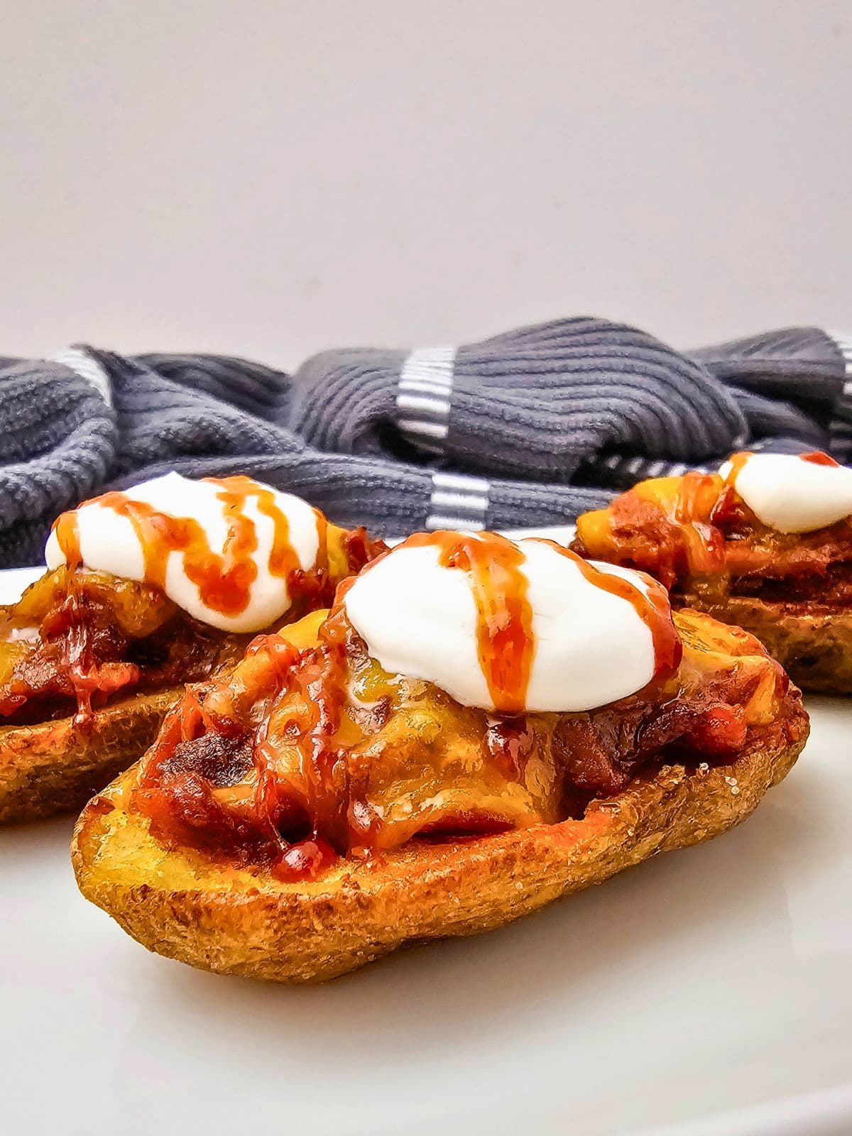 Easy pulled pork potato skins with cheddar cheese, sour cream, and BBQ sauce.