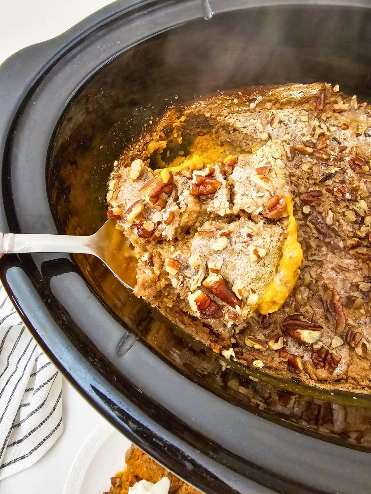 Lifting a slice of pumpkin cake out of the slow cooker.