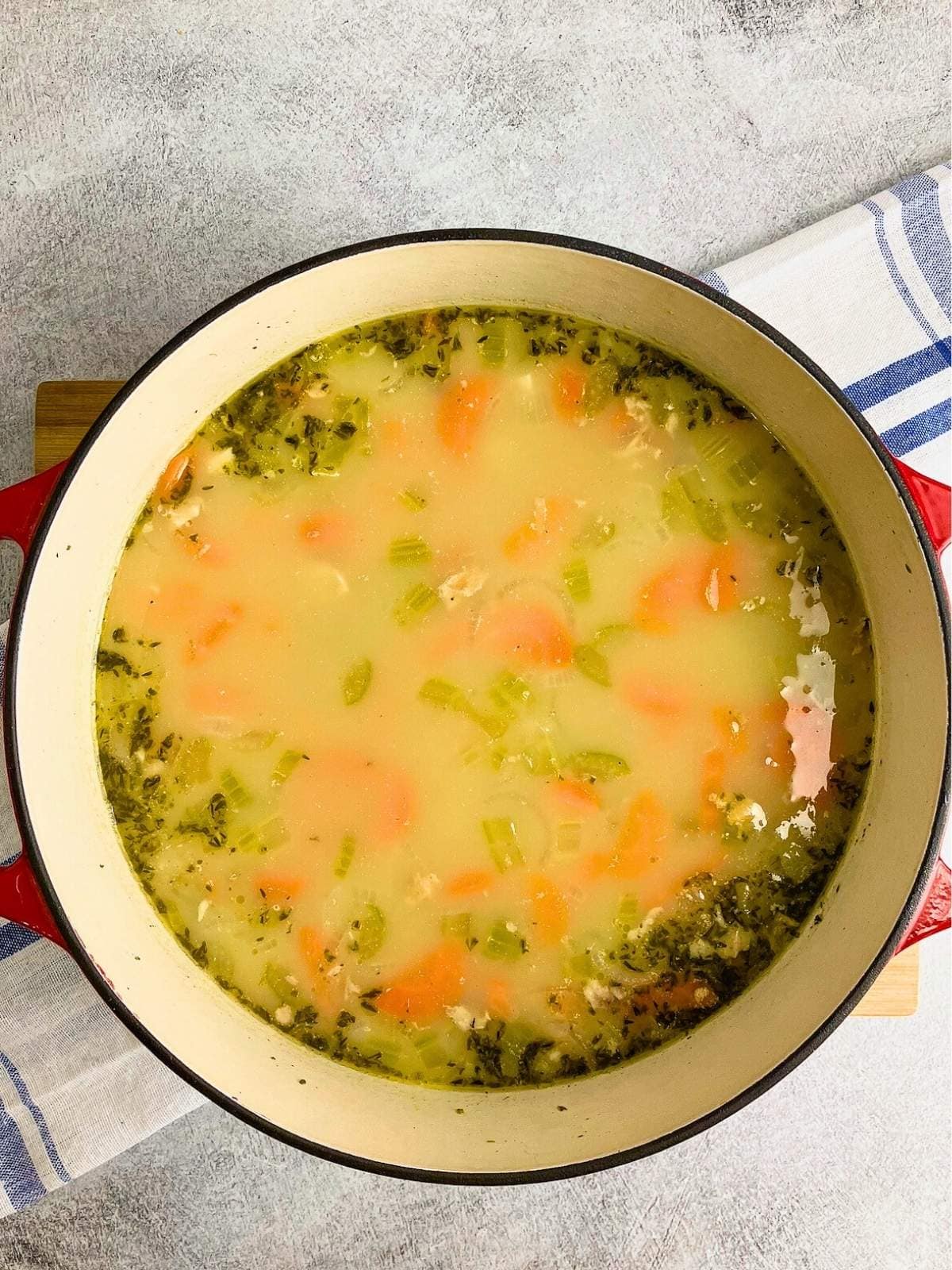 A red and white cast iron pot filled with homemade turkey and rice soup.