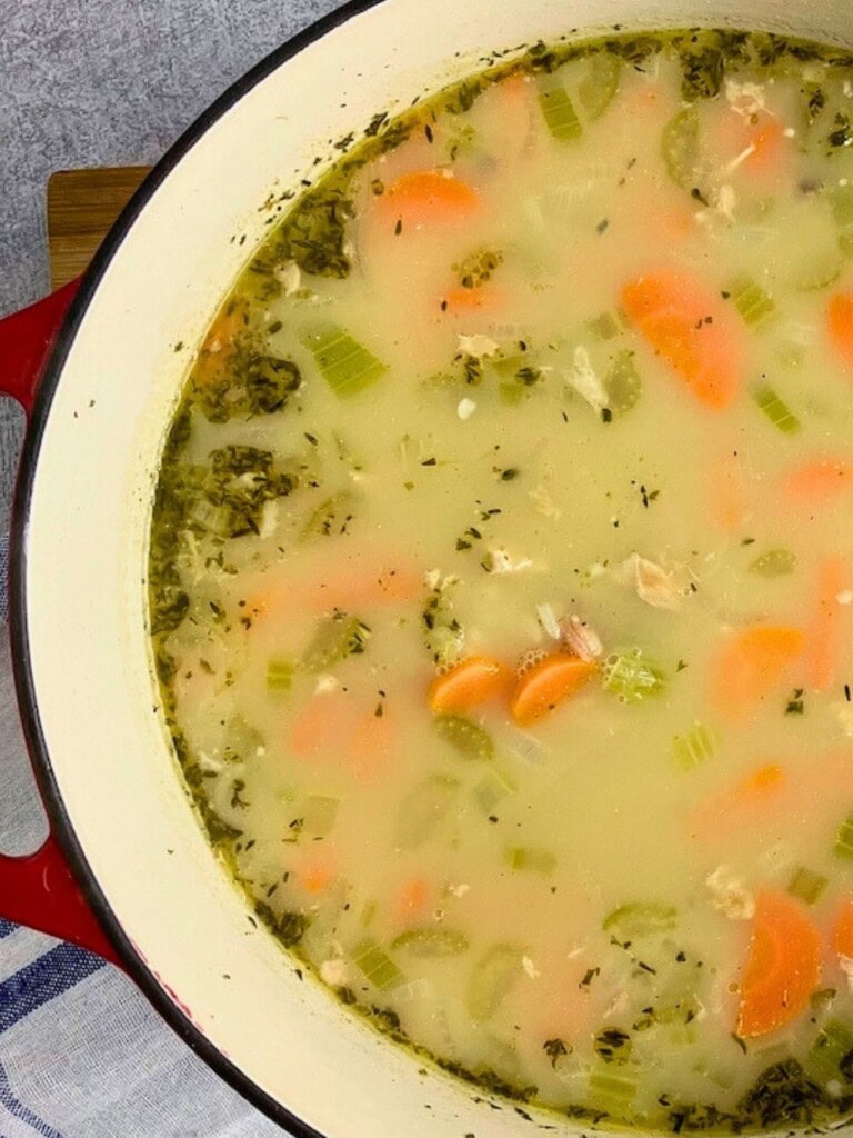 Old fashioned turkey and rice soup in a large red and white cast iron pot.