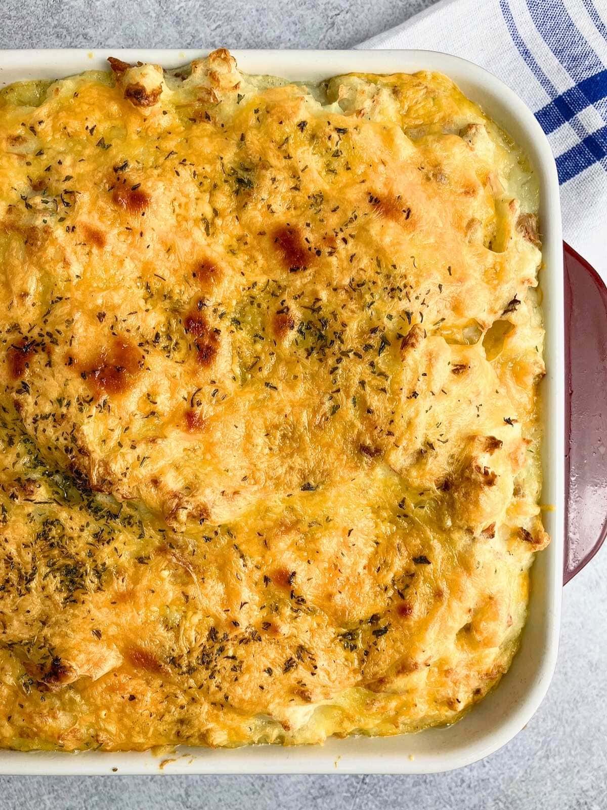 Cheesy turkey bacon loaded mashed potato casserole in a red and white baking dish.