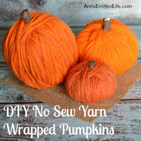 Three yarn wrapped pumpkins are sitting on a square of burlap on the table.