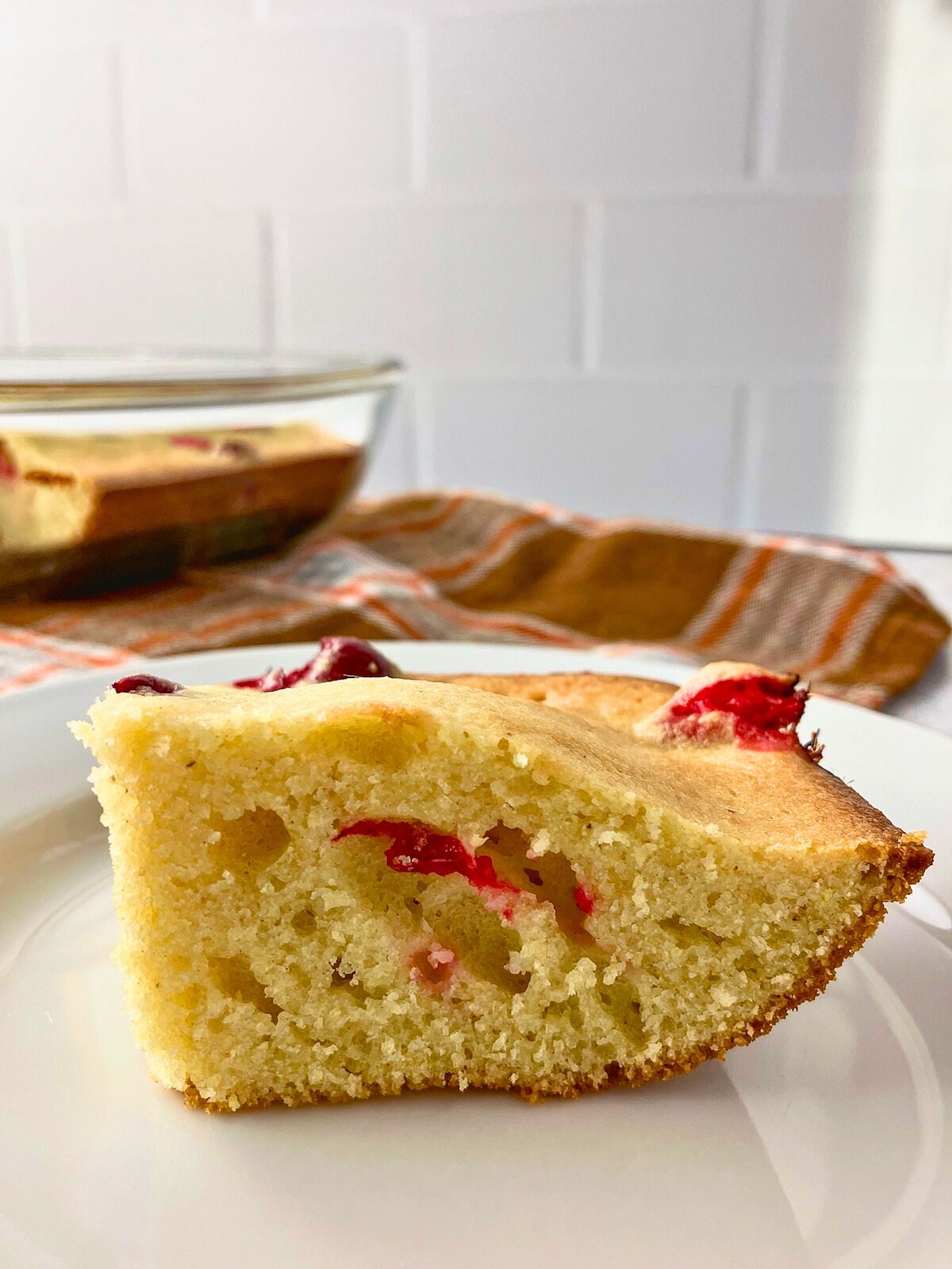 A slice of warm cranberry cornbread on a plate.
