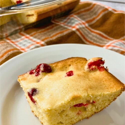 A slice of homemade cranberry cornbread on a plate.
