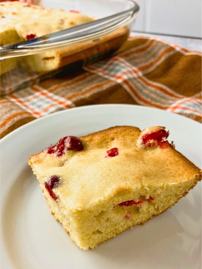 A slice of homemade cranberry cornbread on a plate.