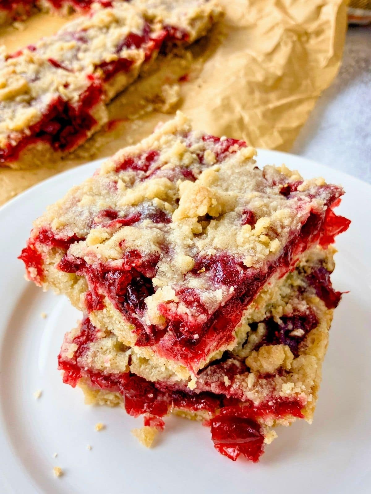 Two cranberry squares stacked on top of each other on a white plate.