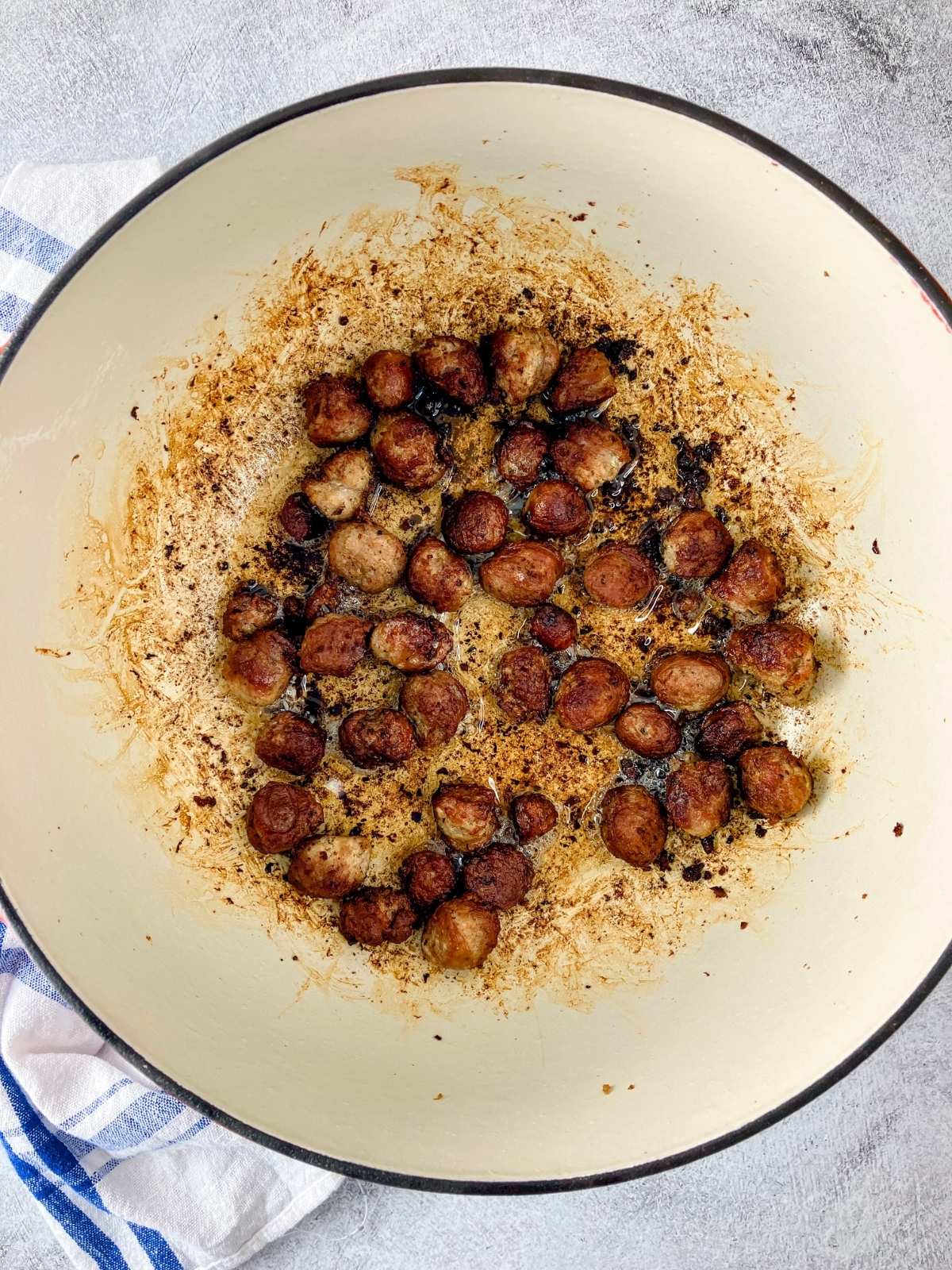 Fried sausage is cooked until browned in a large pot.