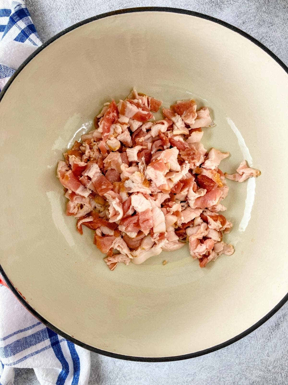 Raw bacon diced and placed into a cast iron Dutch oven.
