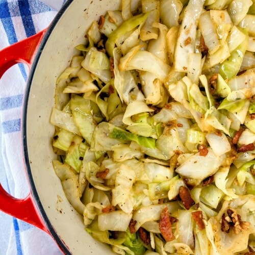Fried cabbage with bacon and onion cooked in a large pot.