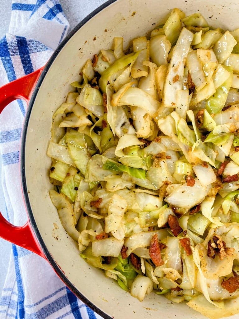 Fried cabbage with bacon and onion cooked in a large pot.