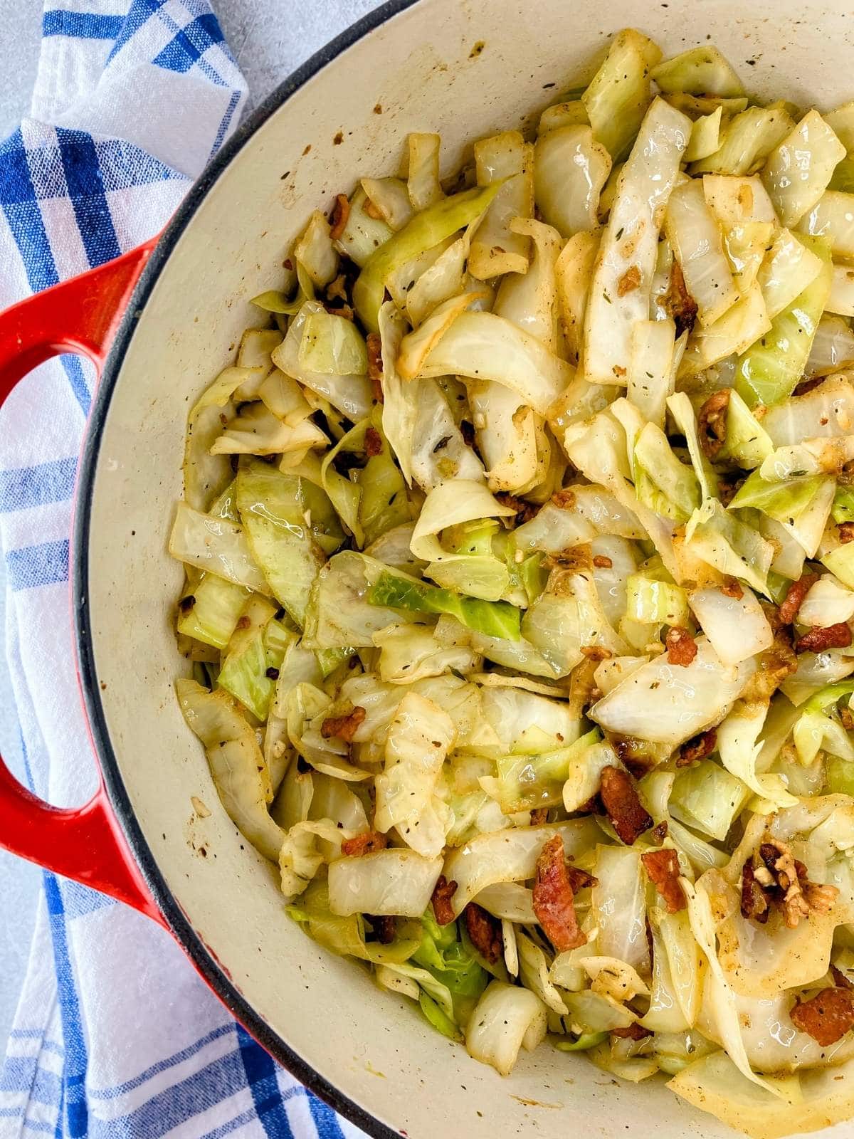 Fried cabbage with bacon and onion cooked in a large pot.