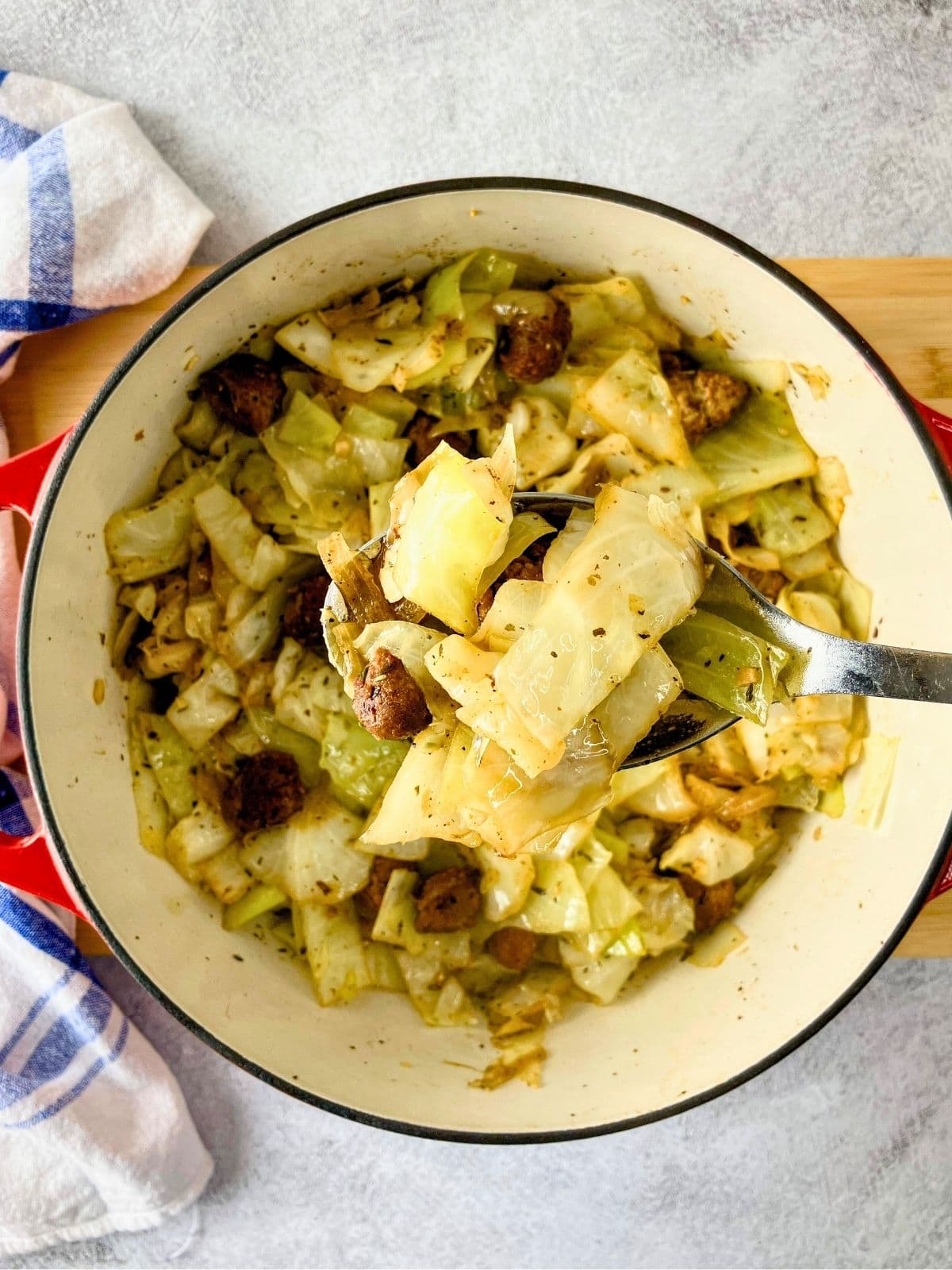 A large Dutch oven of fried cabbage with sausage and onions.