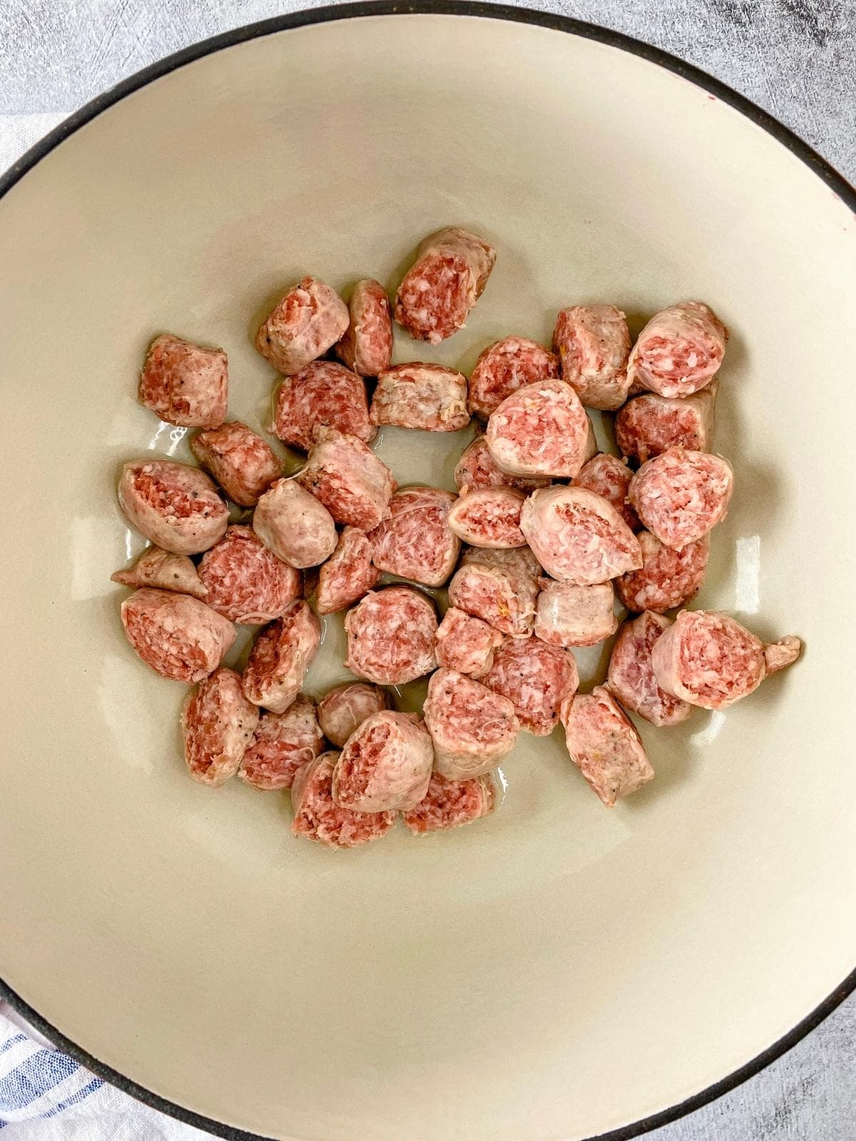 Sliced sausage and vegetable oil in a Dutch oven.