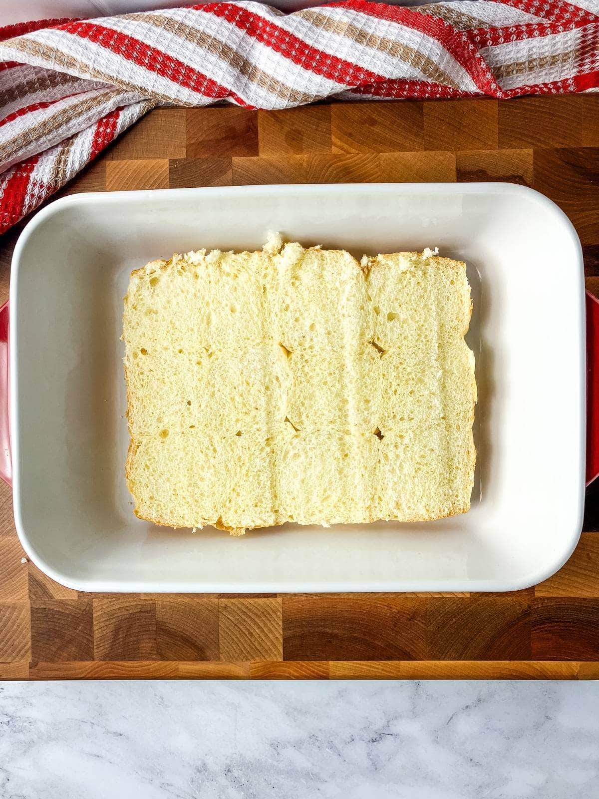 The bottom half of the sliced Hawaiian rolls were placed into a baking dish.