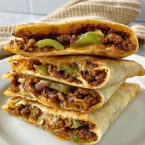 Beef quesadillas made with seasoned ground beef, red onion, green peppers, and cheese sliced and stacked on a plate.