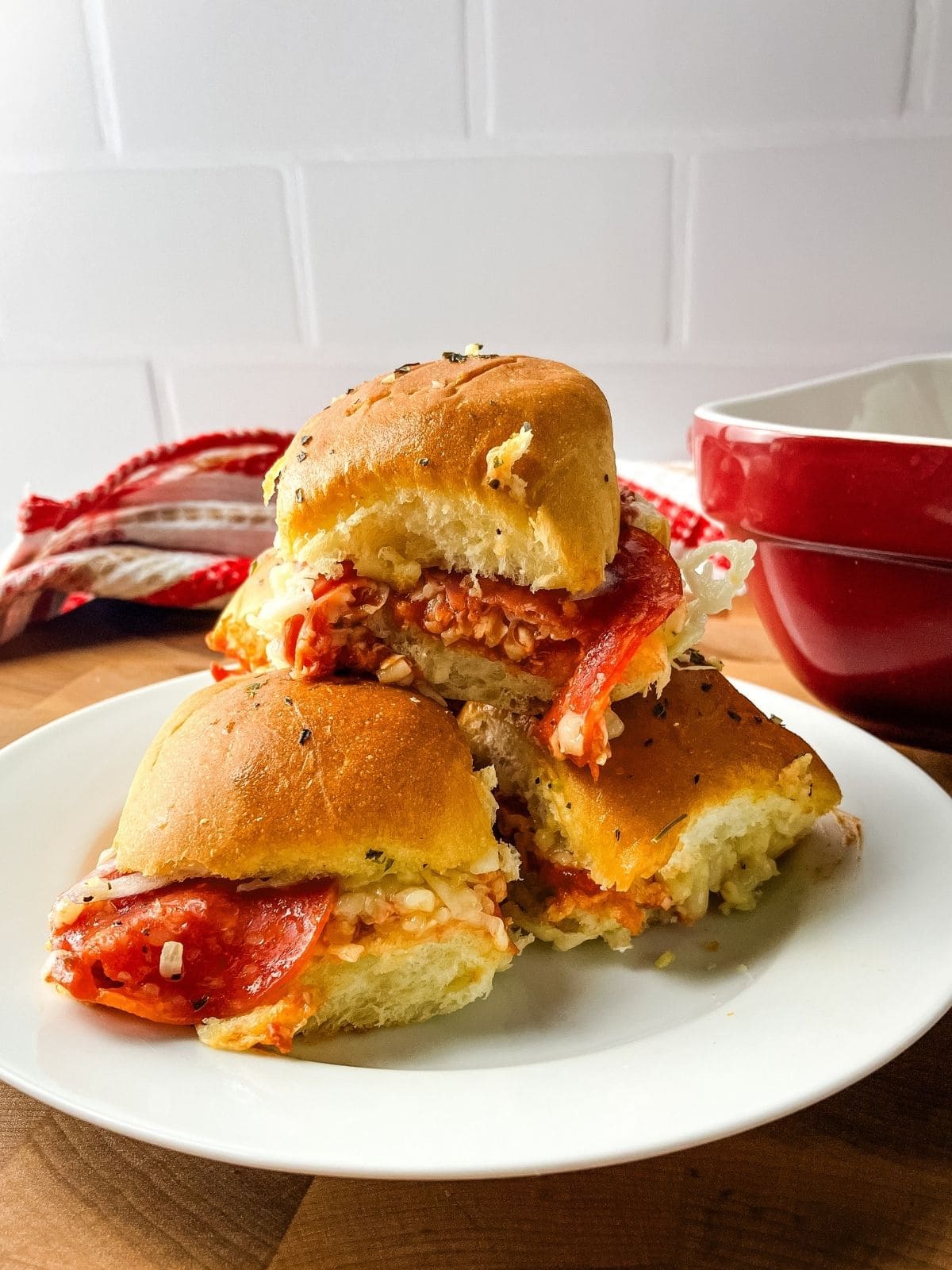 Pizza sliders on Hawaiian rolls stacked on a plate.