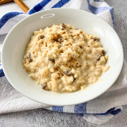 A bowl of homemade baked rice pudding is sitting on a towel on the kitchen counter.