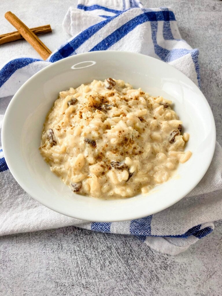 A bowl of homemade baked rice pudding is sitting on a towel on the kitchen counter.