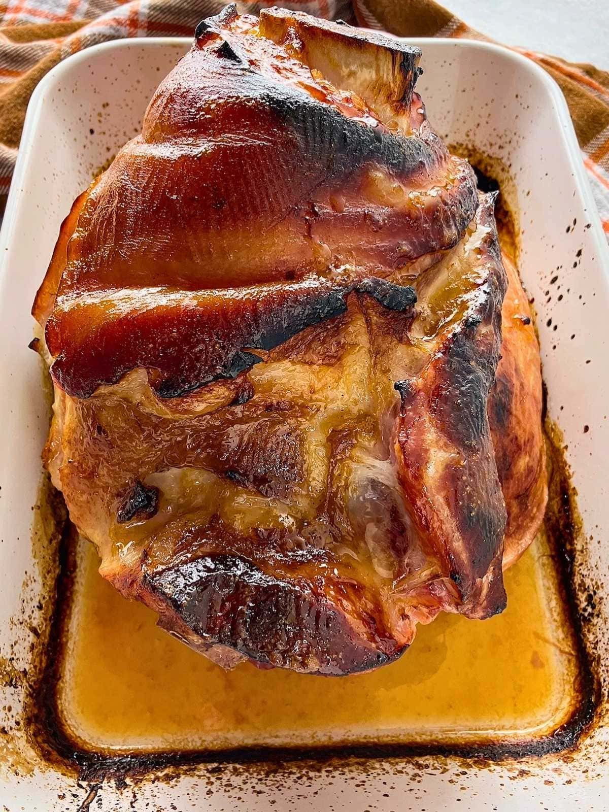 Baked ham with a brown sugar mustard orange glaze in a baking dish.