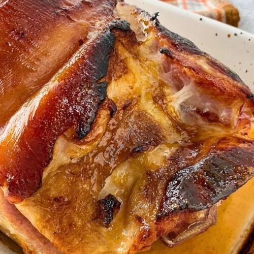 Baked ham with a brown sugar mustard orange glaze in a baking dish.