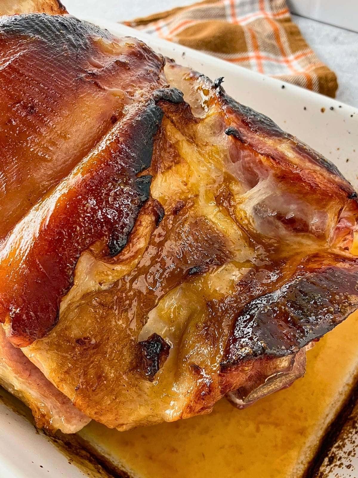 Baked ham with a brown sugar mustard orange glaze in a baking dish.