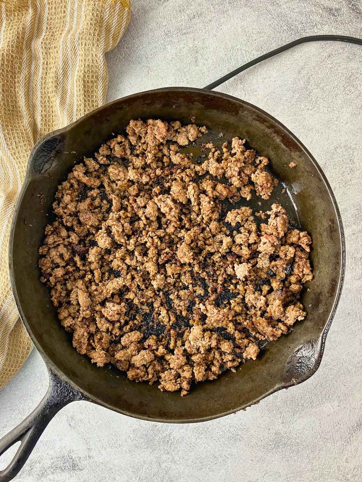 Browning the ground beef in a cast iron skillet.