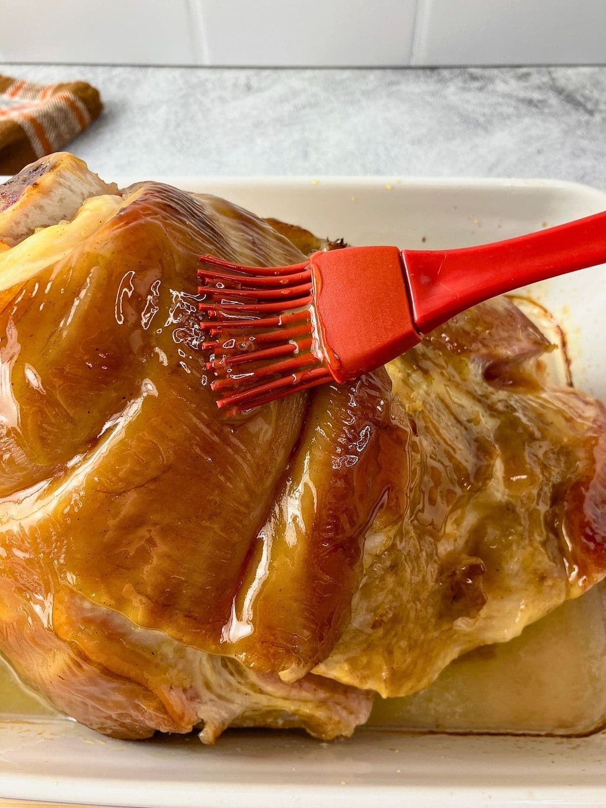 Basting the ham with the brown sugar mustard glaze.