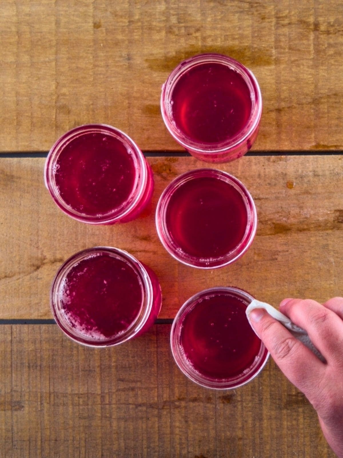 Wiping the rims of the jelly jars clean with a damp paper towel.