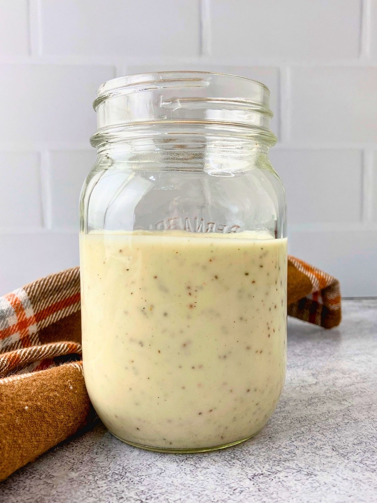 A jar of homemade creamy coleslaw dressing is sitting on the counter.