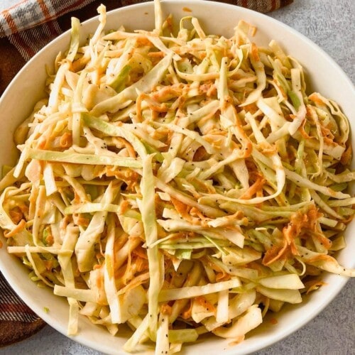 A white serving bowl of homemade creamy coleslaw.