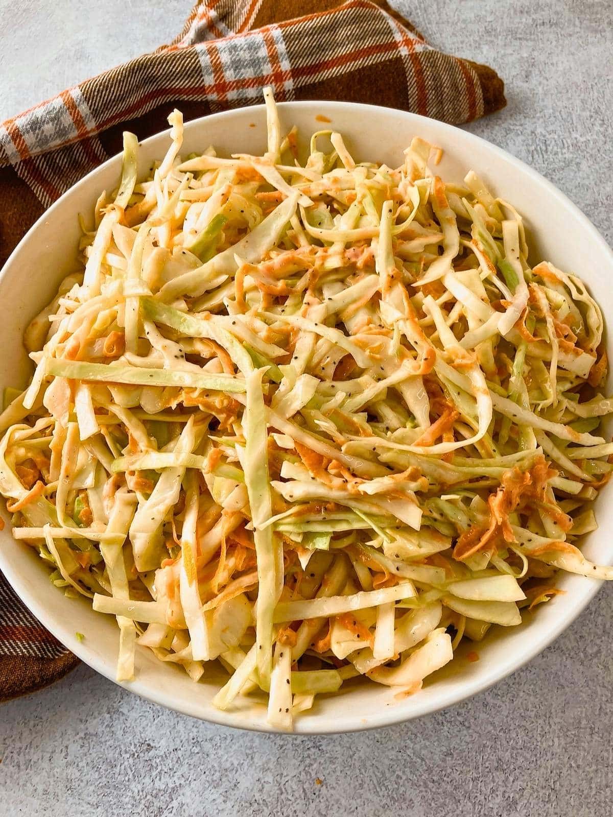 A white serving bowl of homemade creamy coleslaw.