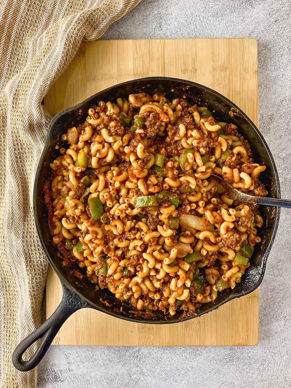 The cooked pasta was added to the meat sauce in the skillet and mixed together.
