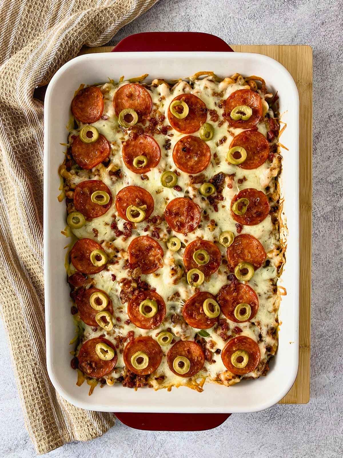 A 9x13 casserole dish of pizza pasta bake is cooling on the counter.