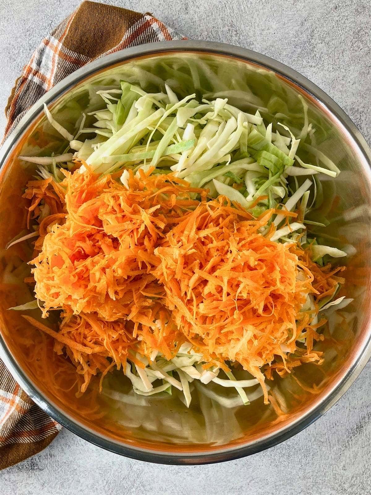 The shredded carrot was added to the bowl of cabbage.
